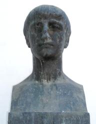 a dark marble statue of man, non distinct features, worn away.