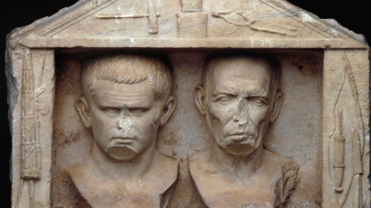 a ancient statue of two men's faces, latin text beneath them