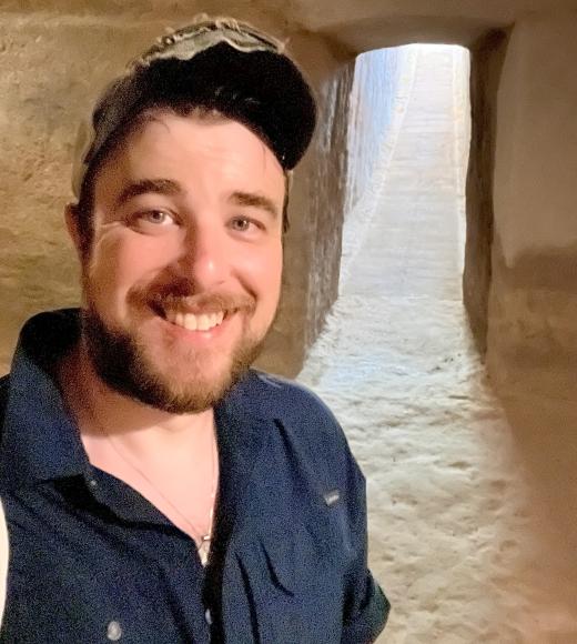 A photo of a man wearing a blue shirt and a hat.