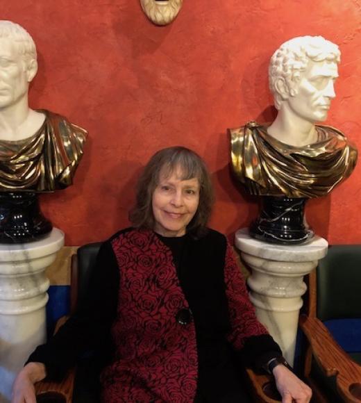 Emily Albu sitting between two ancient busts
