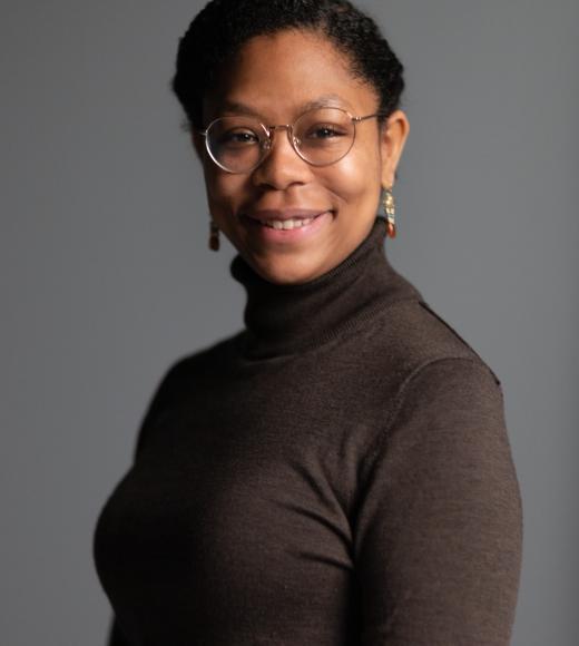 Bianca wearing glasses and earrings looking at the camera