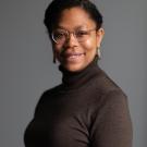 Bianca wearing glasses and earrings looking at the camera