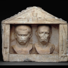 a ancient statue of two men's faces, latin text beneath them