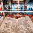 An old bible lays open in a museum display case