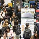 Many students crowd around employers and their banners at a career fair